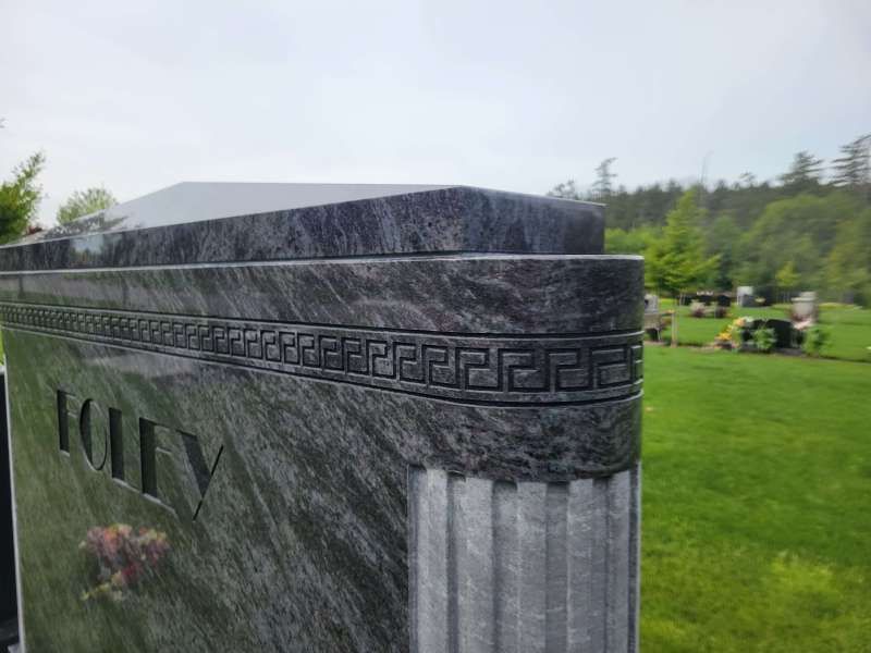 a gravestone with a greek key design on it is in a cemetery .