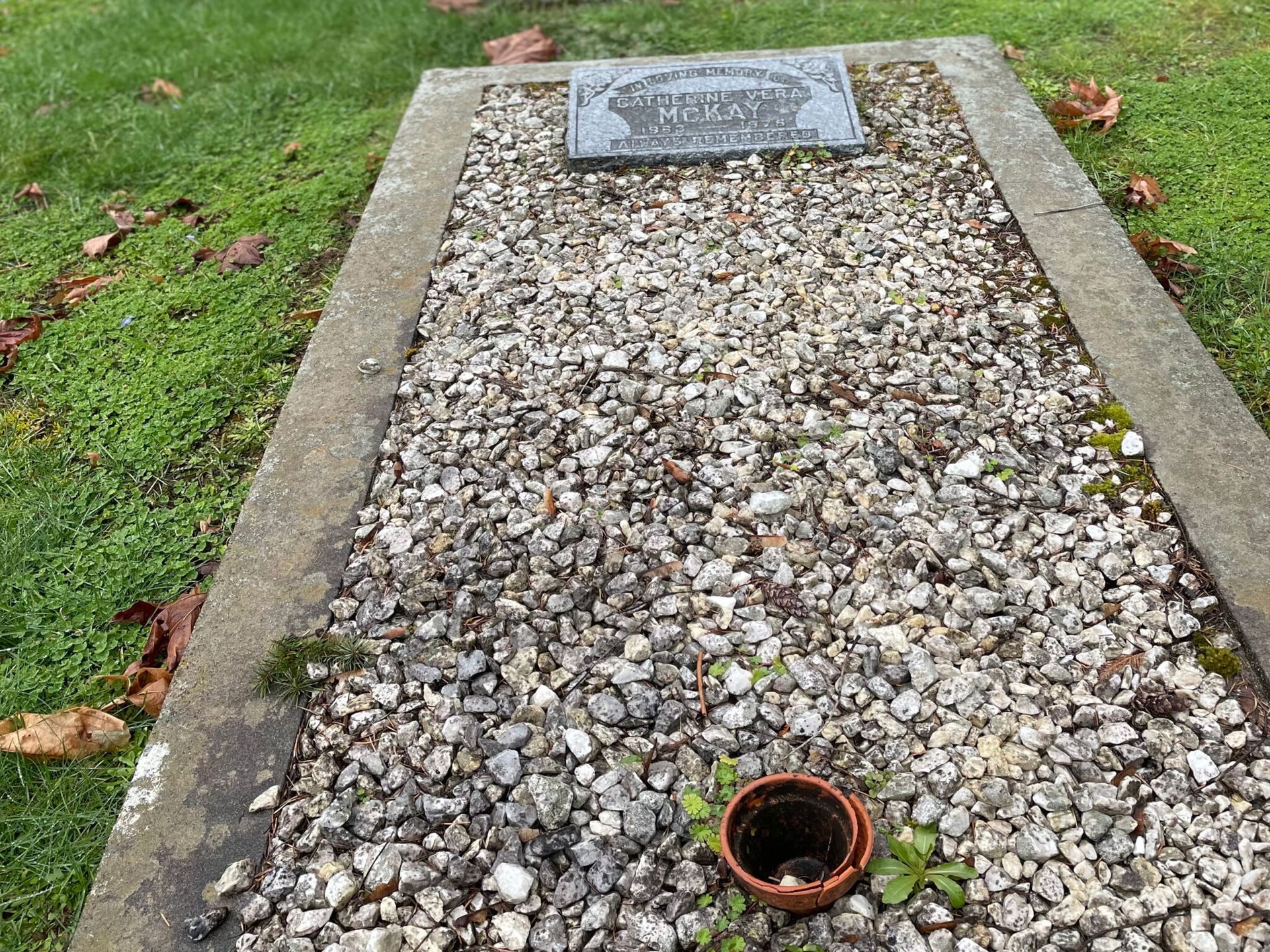 a graveyard with gravel and grass and a pot in the middle .