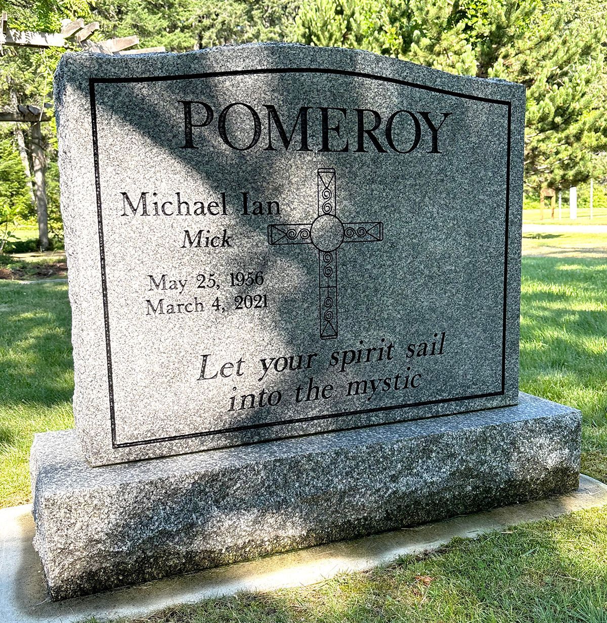 a large gravestone in a cemetery with a cross on it .