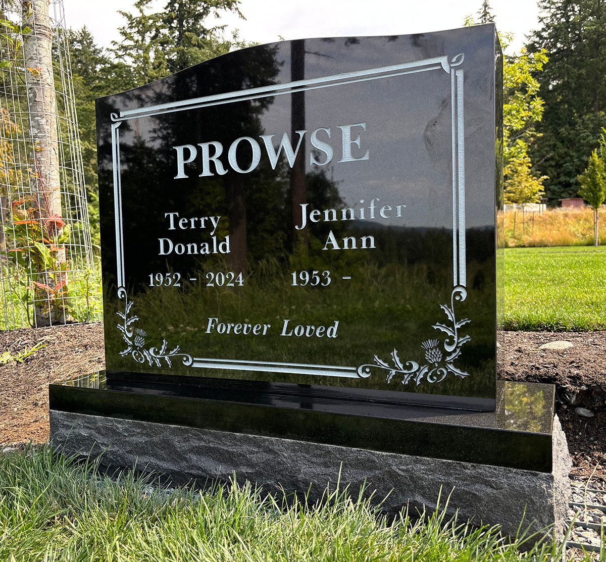 Photo of a black upright granite memorial marker with white lettering and thistle graphics.