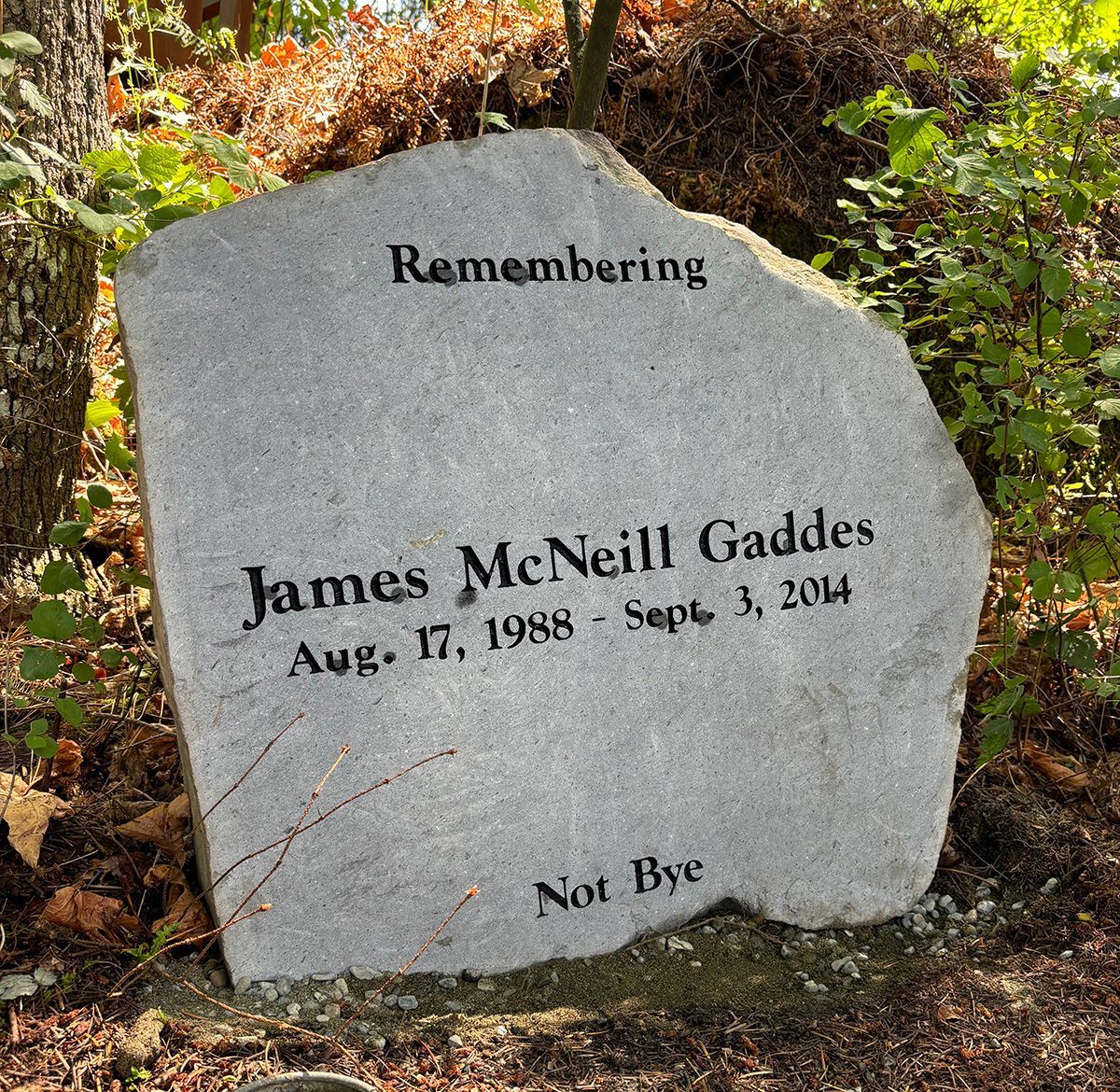 Photo of a natural grey basalt boulder memorial monument marker with black lettering