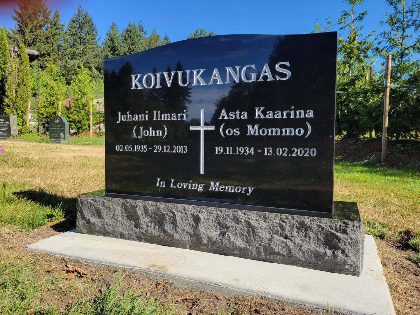 a black gravestone with a cross on it is in a cemetery .