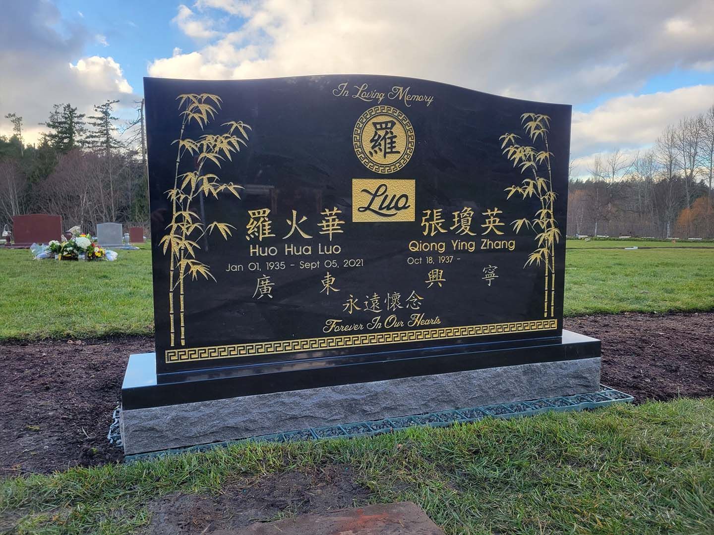 a black gravestone with chinese writing on it in a cemetery