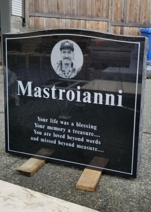 a black gravestone with a picture of a man and the name mastroianni