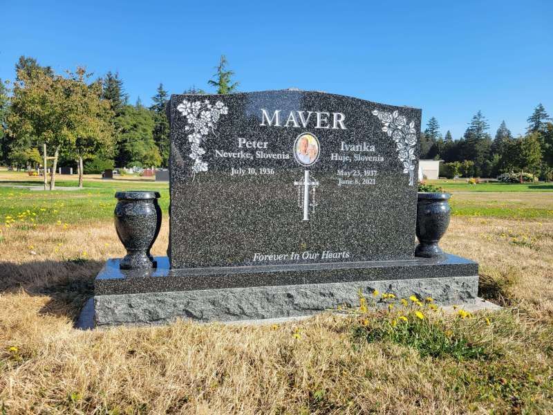 a black gravestone with two vases in a cemetery .