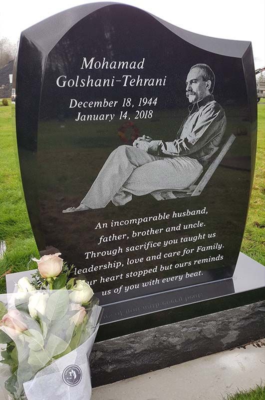 A black gravestone with a picture of a man sitting in a chair.