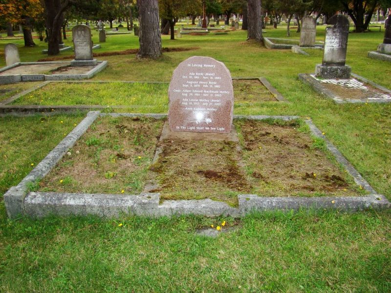 a grave in a cemetery with trees in the background