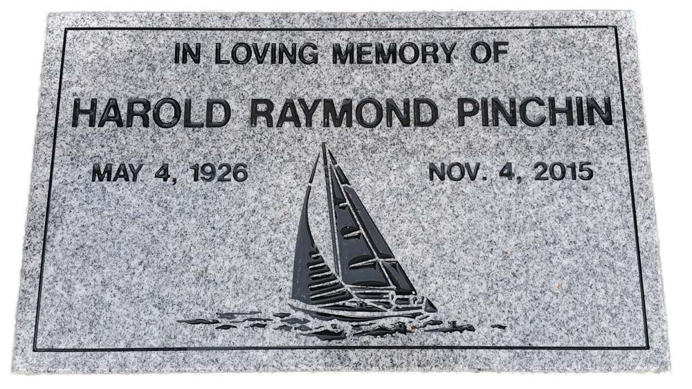 A grave marker for harold raymond pinchin with a sailboat on it.