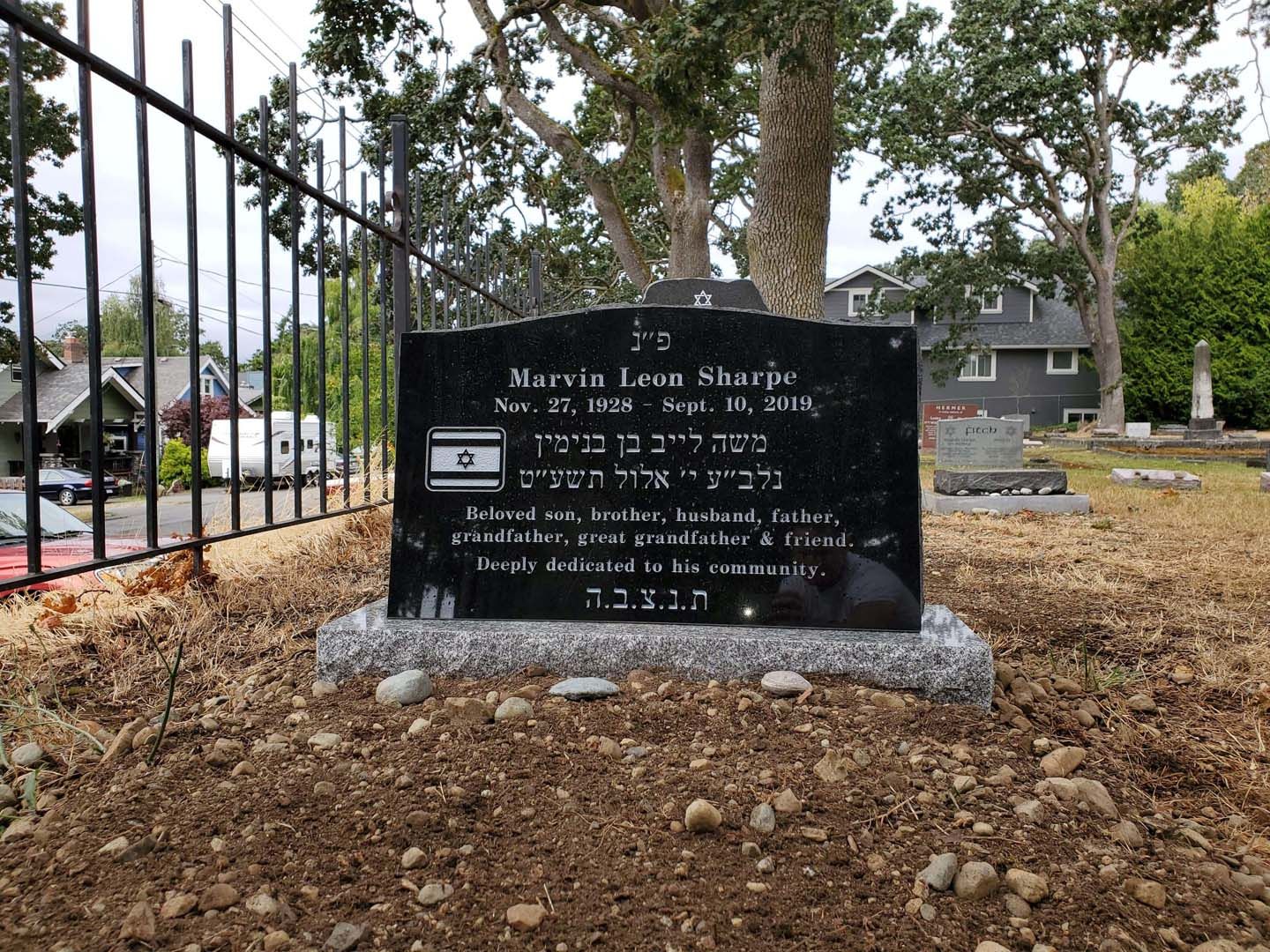 a gravestone in a cemetery with a fence in the background .