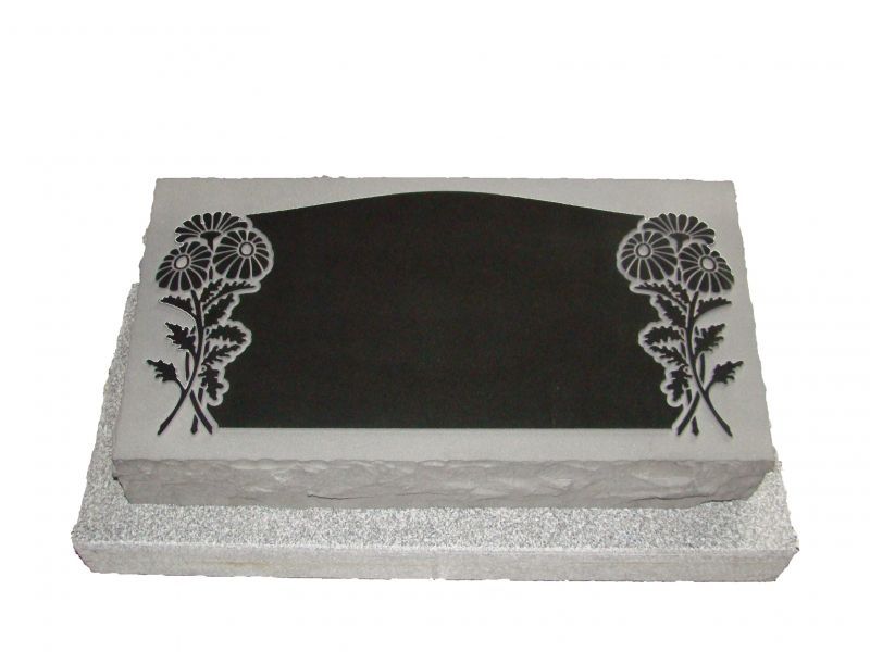 A black and white gravestone with flowers on it