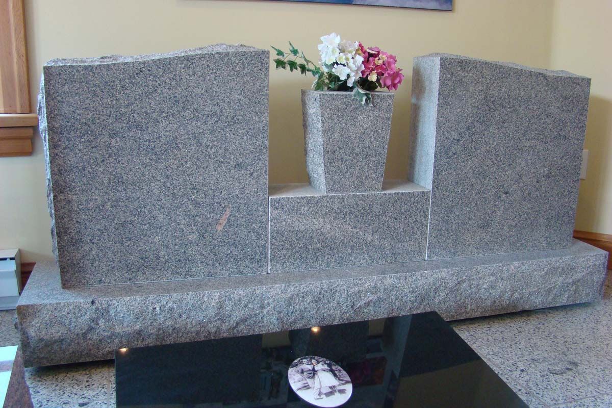a gravestone with a vase of flowers on top of it
