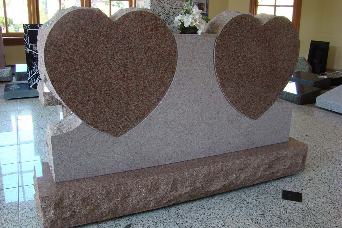a gravestone with two hearts carved into it