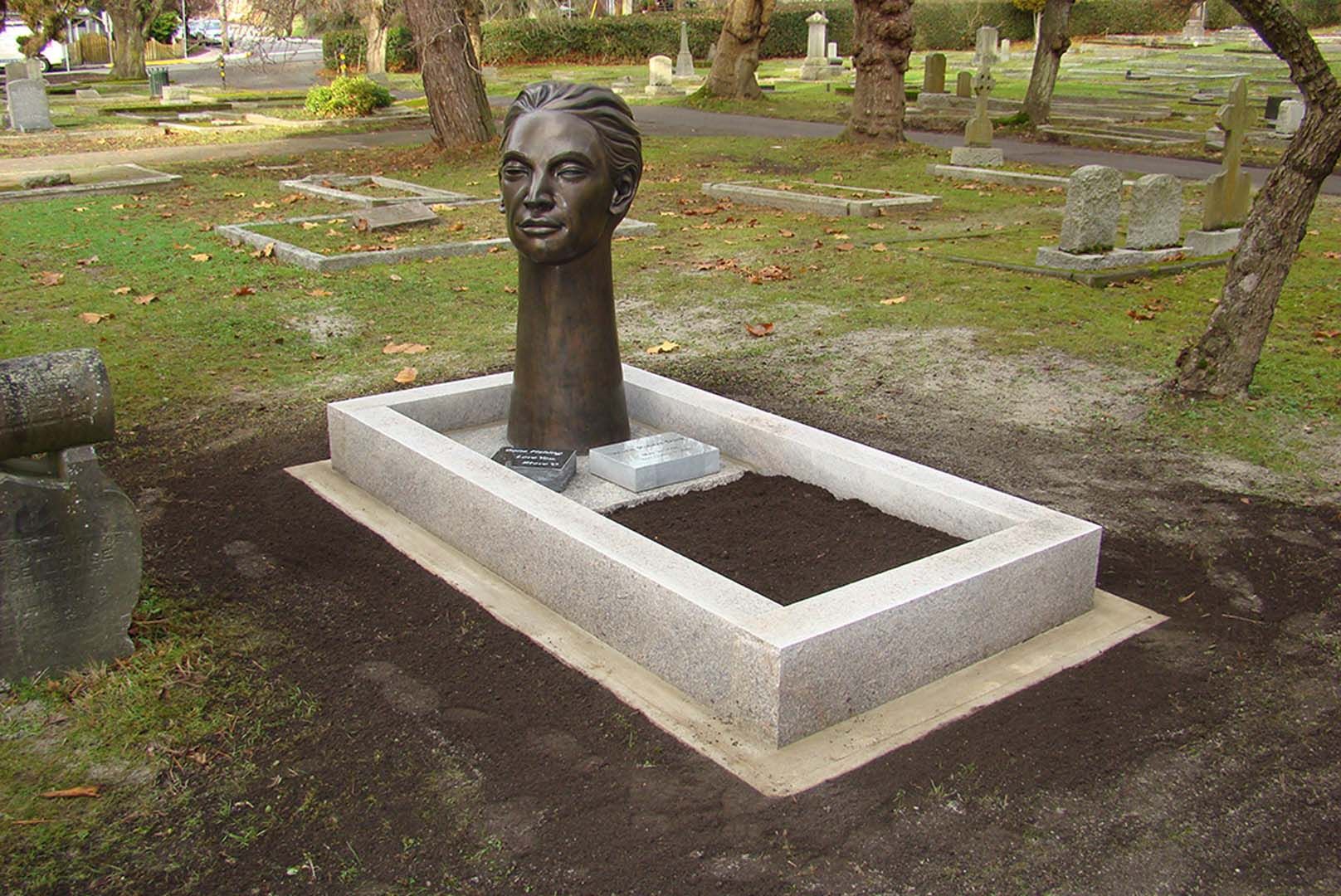 a grave with a statue of a woman 's head on it