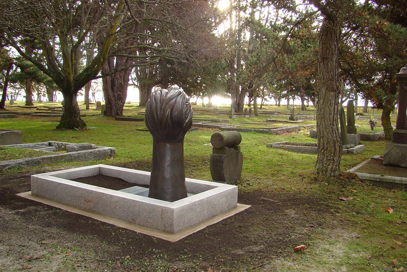 a grave in a cemetery with trees in the background