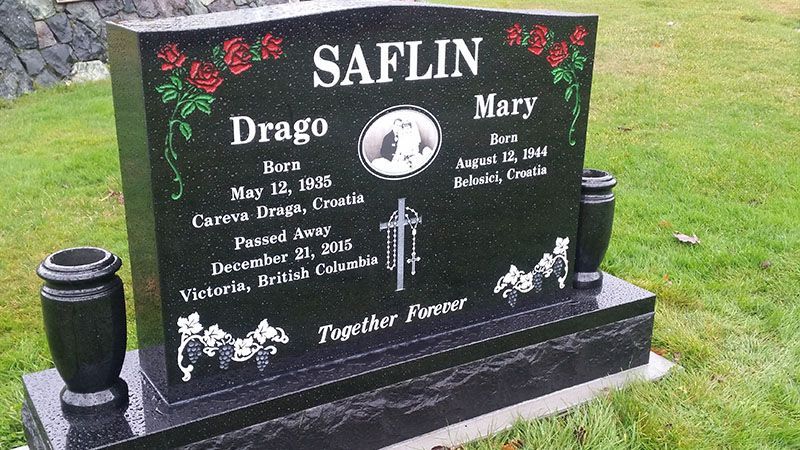 A black gravestone for drago and mary is in a cemetery.
