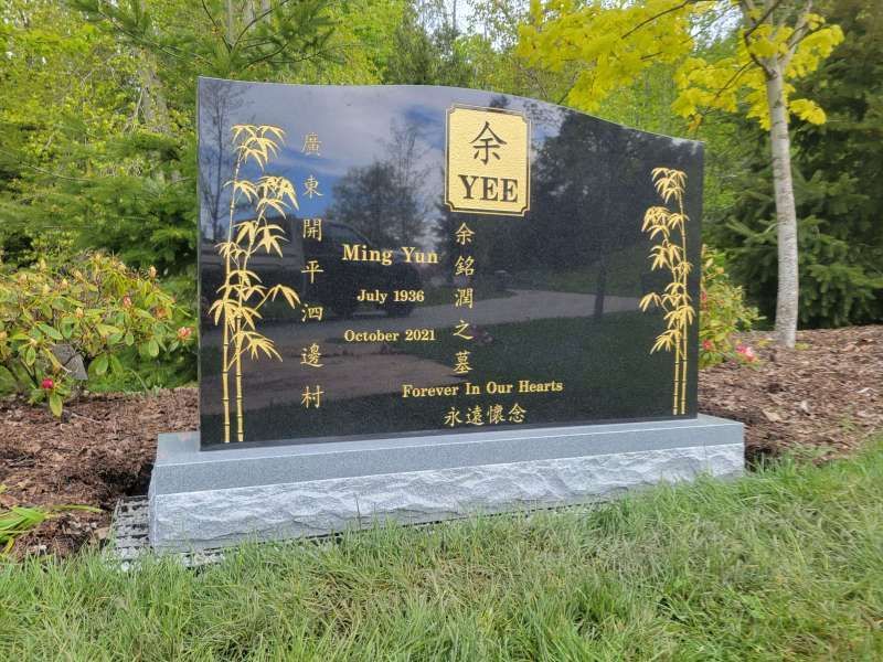 a black and gold gravestone for yee sitting in the grass