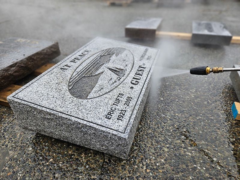 A gravestone is being cleaned with a high pressure washer.