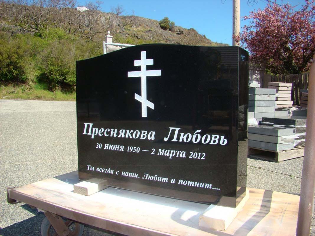 A black gravestone with a white cross on it