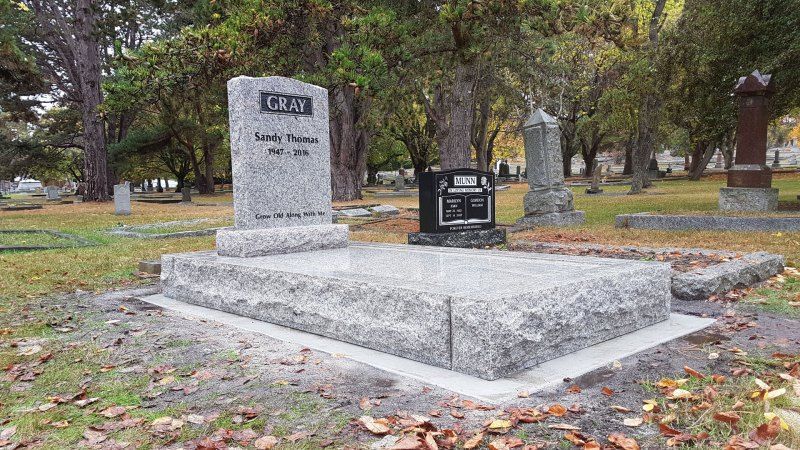 a gravestone in a cemetery with trees in the background .