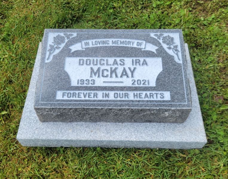 A gravestone for douglas ira mckay is in the grass