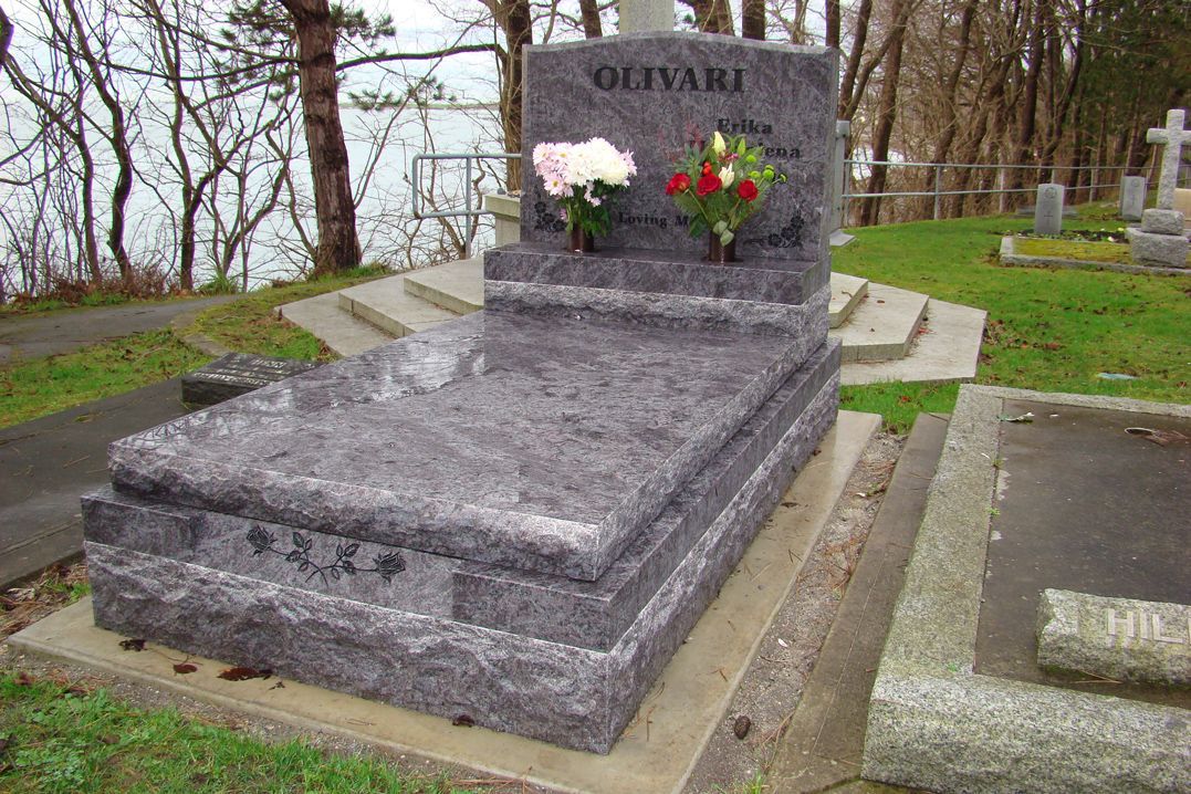 a gravestone in a cemetery with flowers on it .