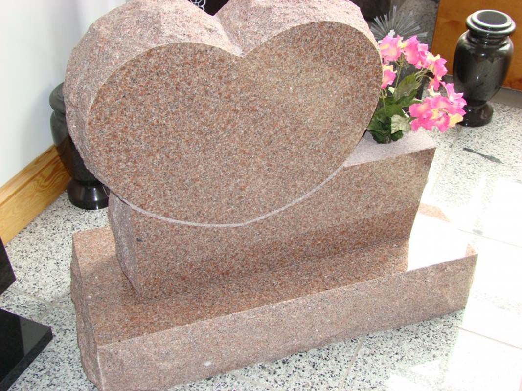 A heart shaped gravestone with pink flowers in it