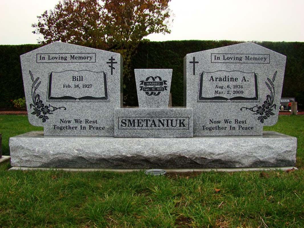 A couple of graves in a cemetery with a tree in the background.