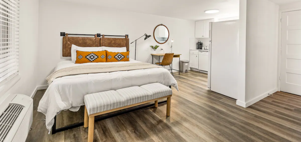 A hotel room with a king size bed and a bench.