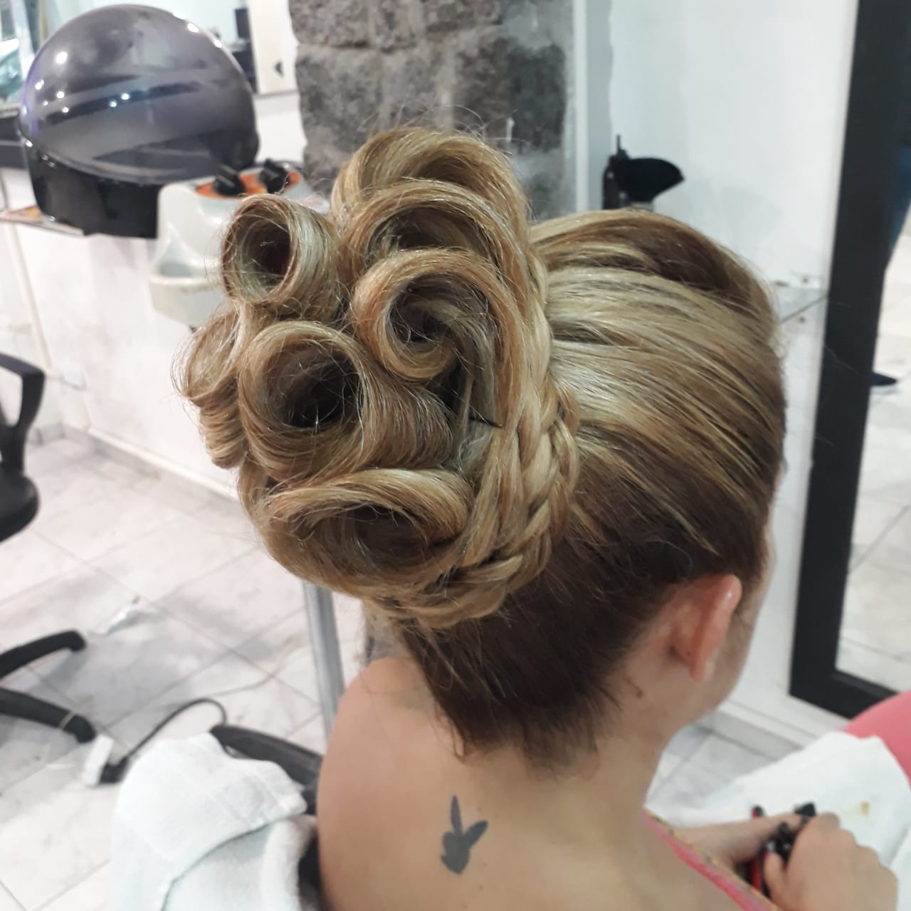 Una mujer con un tatuaje de Playboy en la espalda lleva el pelo recogido en un moño.