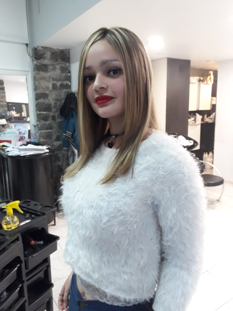 Una mujer con un suéter blanco está parada en un salón.