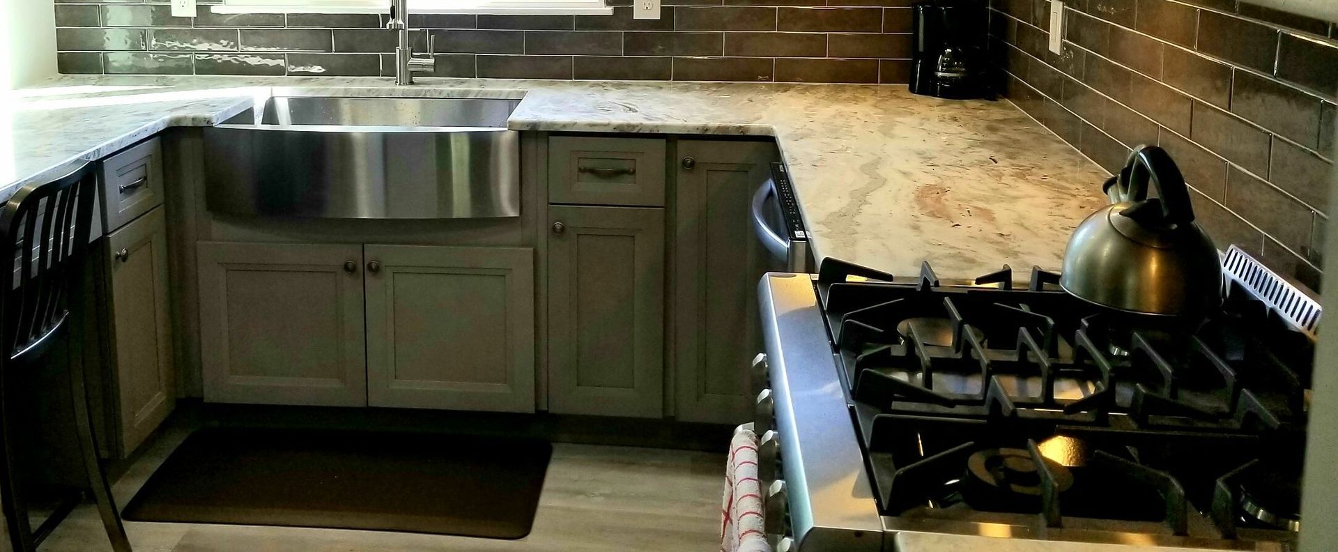 Kitchen with stainless steel sink, gray cabinets, granite countertops, and a stove.