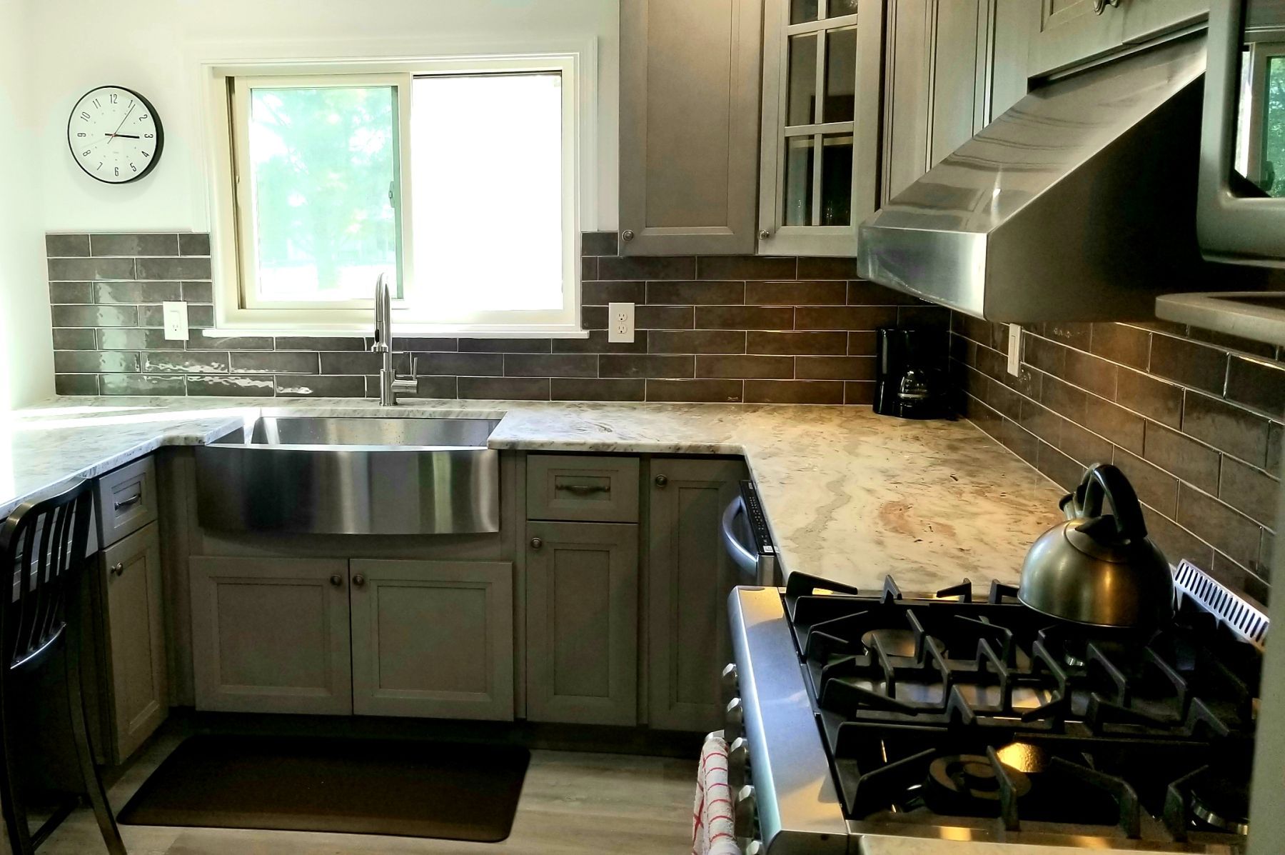 Kitchen with gray cabinets, stainless steel sink and range, and granite countertops.