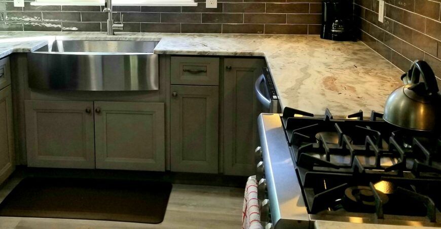 Kitchen with stainless steel sink, gray cabinets, granite countertops, and gas stove.