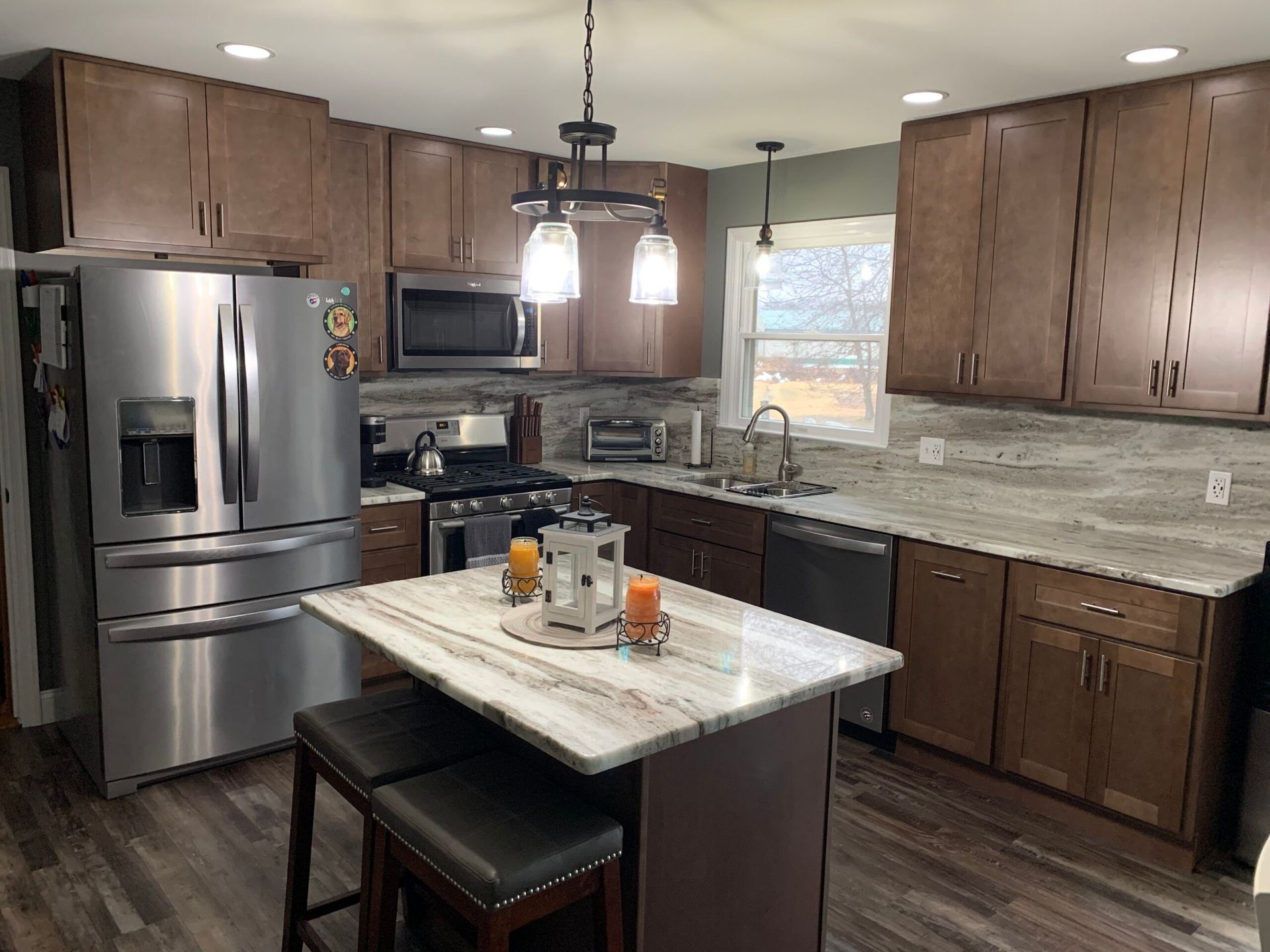 Modern kitchen with stainless steel appliances, brown cabinets, and an island with a marbled countertop.