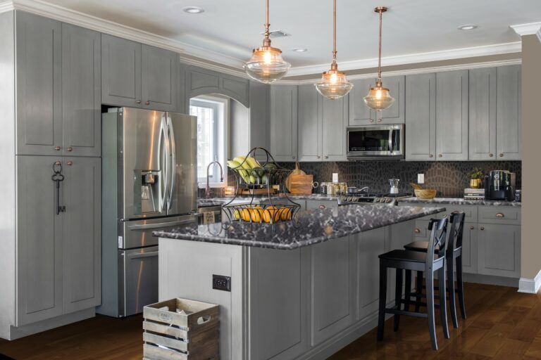 Gray kitchen with an island, stainless steel appliances, and pendant lights.