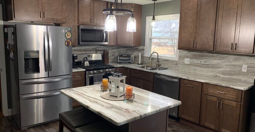 Kitchen with brown cabinets, stainless steel appliances, island with seating, and light countertops.