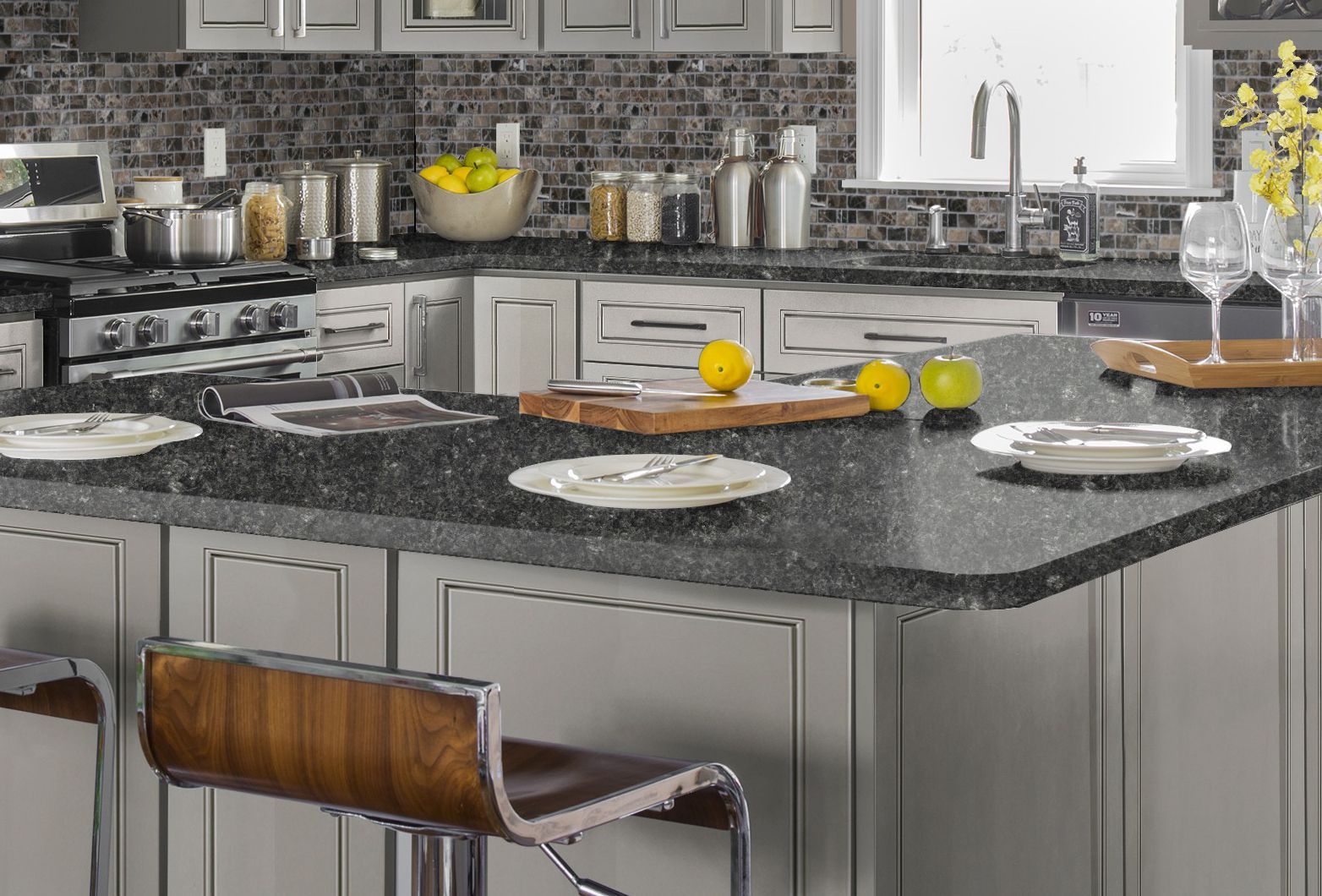 Gray kitchen with island and bar stools, granite countertops, stainless steel appliances, and backsplash.