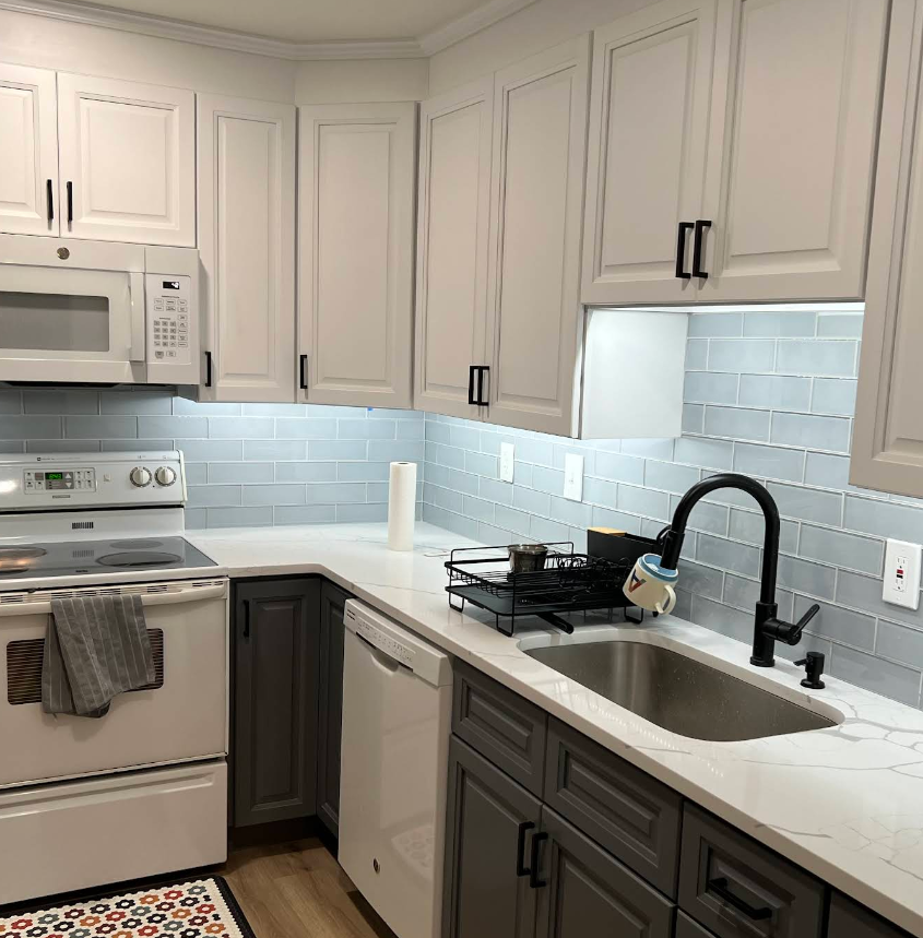 Kitchen with white cabinets, gray lower cabinets, and a gray tiled backsplash.
