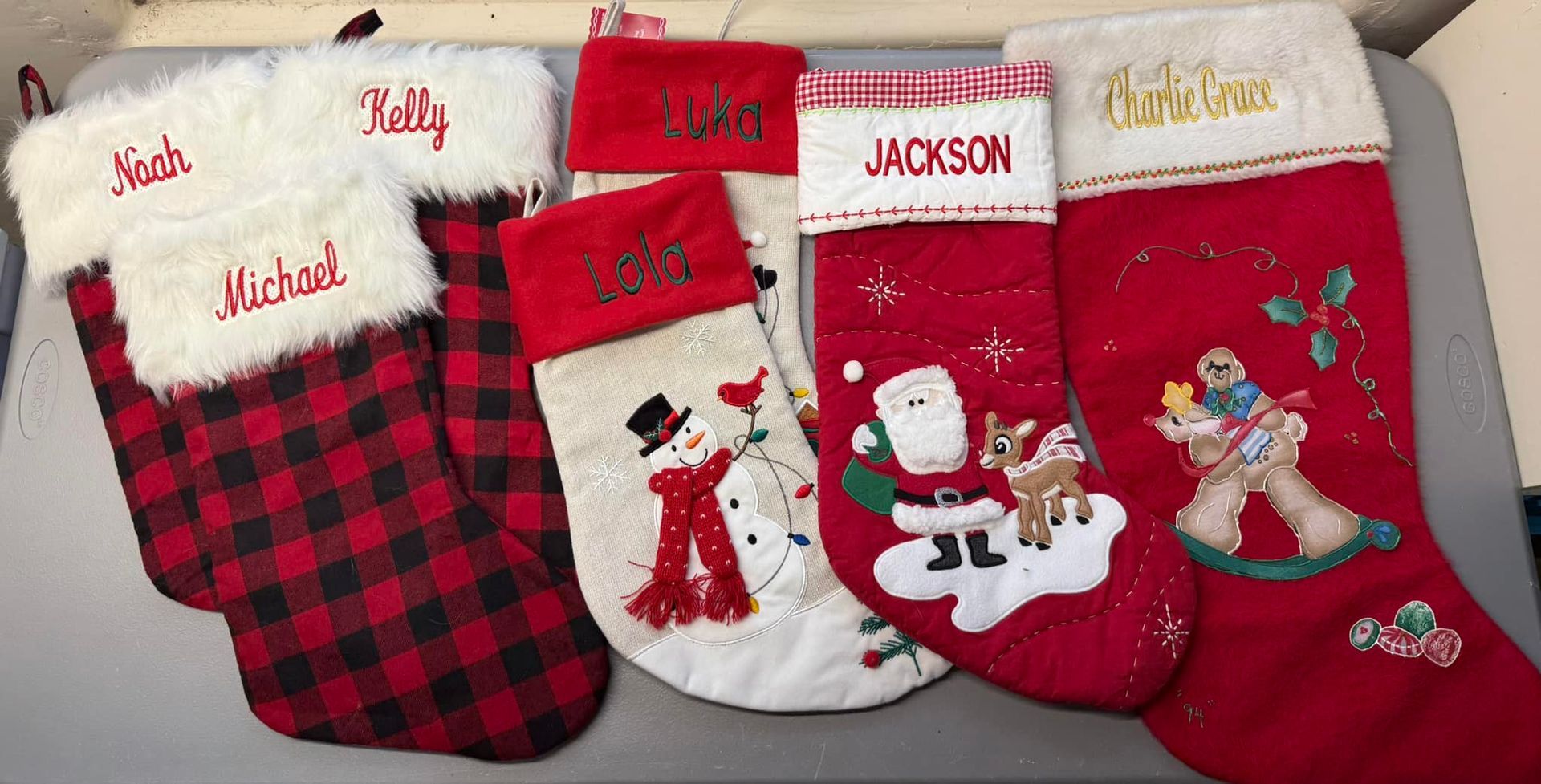 Six personalized Christmas stockings: red and white, names embroidered.