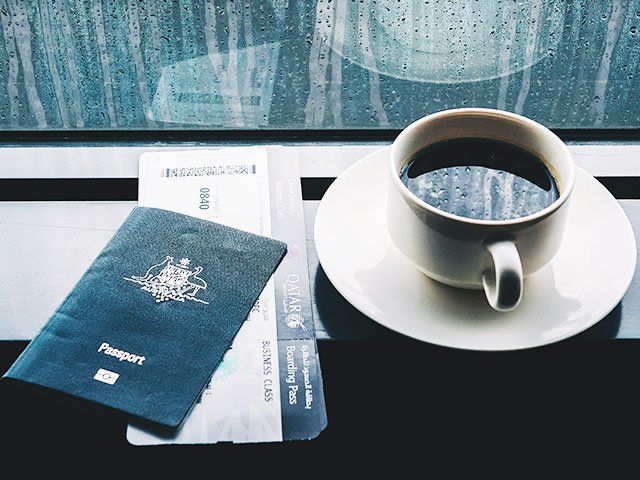 Passport, airplane ticket and coffee by a rainy window
