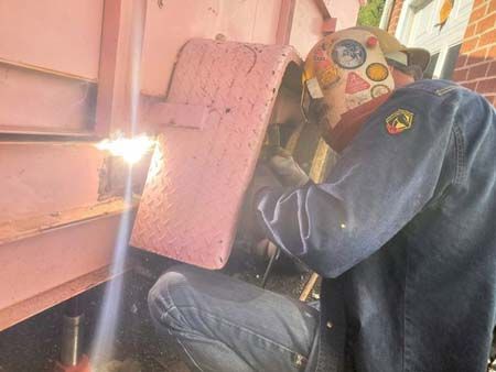 A man is welding a piece of metal with a torch.