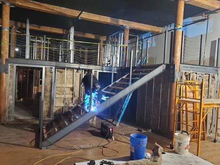 A man is welding a staircase in a building under construction.
