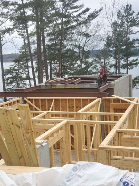 A man is sitting on the roof of a house under construction.