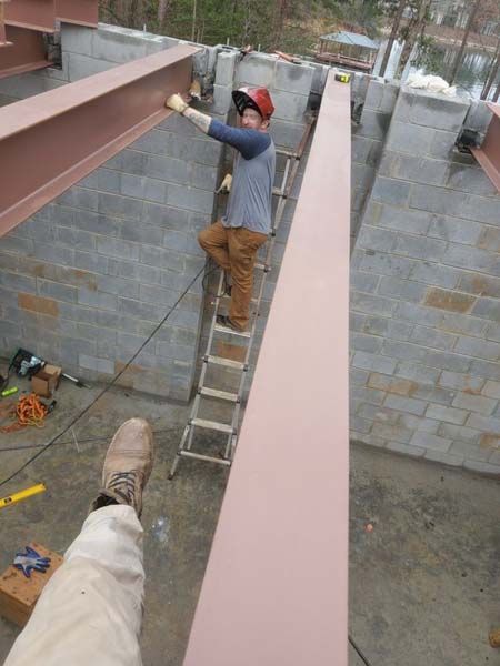 A man is standing on a ladder working on a beam