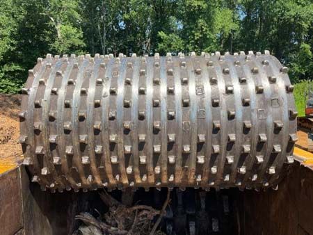 A large metal roller with spikes on it is sitting in a bucket.