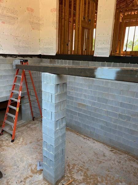 A ladder is sitting next to a brick wall in a room under construction.