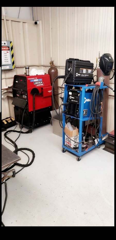 A welding machine is sitting on a cart in a room.
