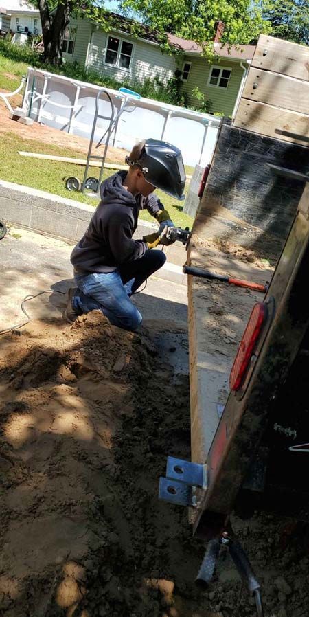 A man wearing a helmet is working on a trailer.