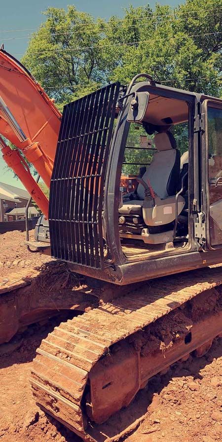 A man is driving a large excavator on a dirt road.
