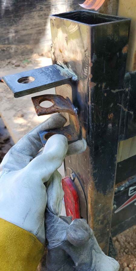 A person wearing gloves is holding a piece of metal in their hand.
